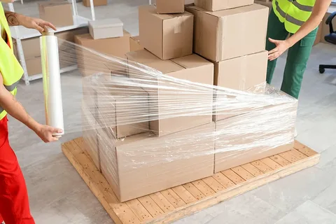 Pallets wrapped in clear stretch film, warehouse background